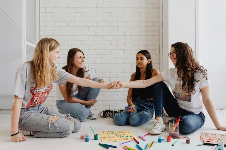 four s sitting on the ground with one holding the other hand