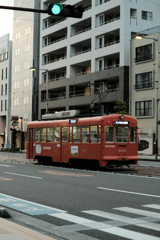 there is a red trolley on the street with buildings behind it