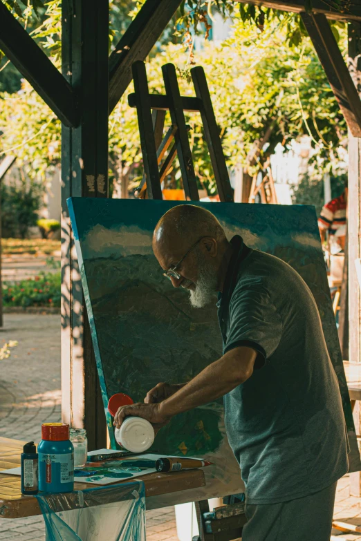 the man is painting a large blue piece of artwork