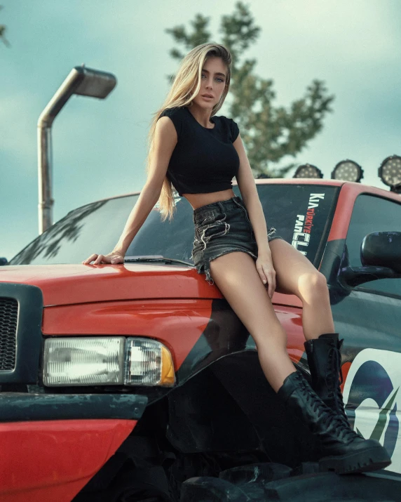 young woman with boots sitting on truck in front of a building