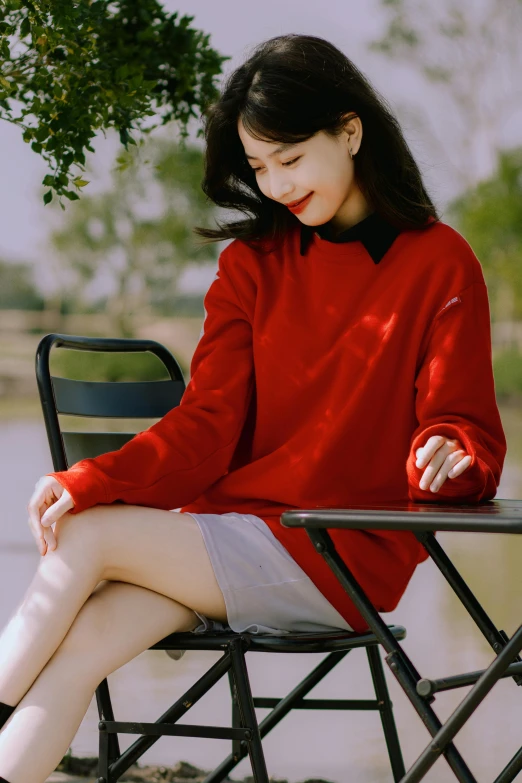 a girl wearing a red sweater is sitting in a folding chair