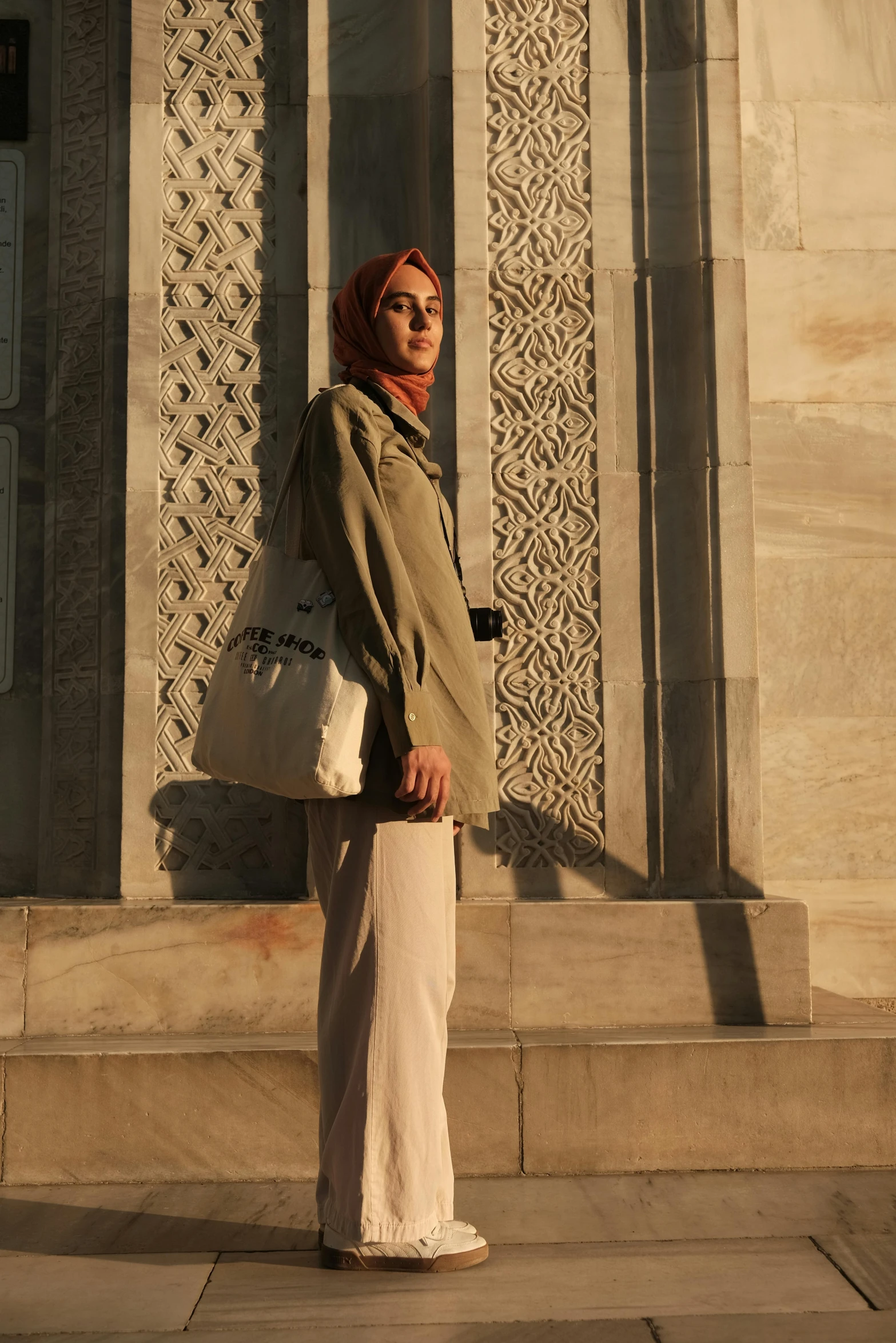 an elderly woman in a long robe stands in front of a large structure