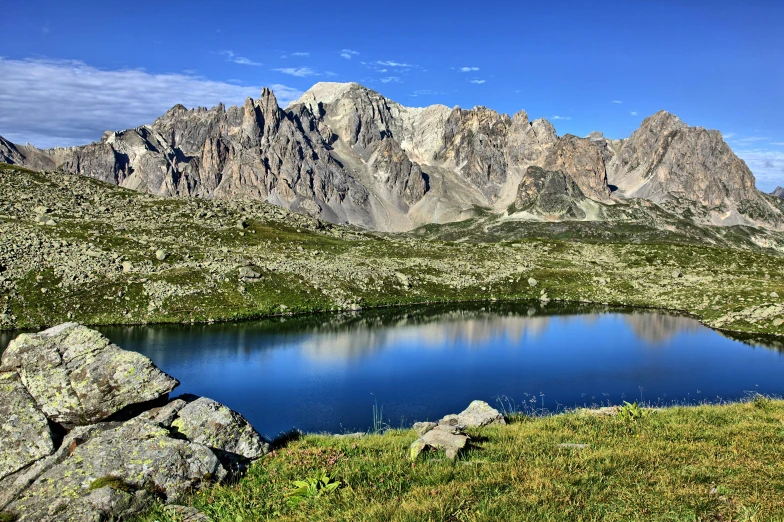 a field with a lake and mountains in the background