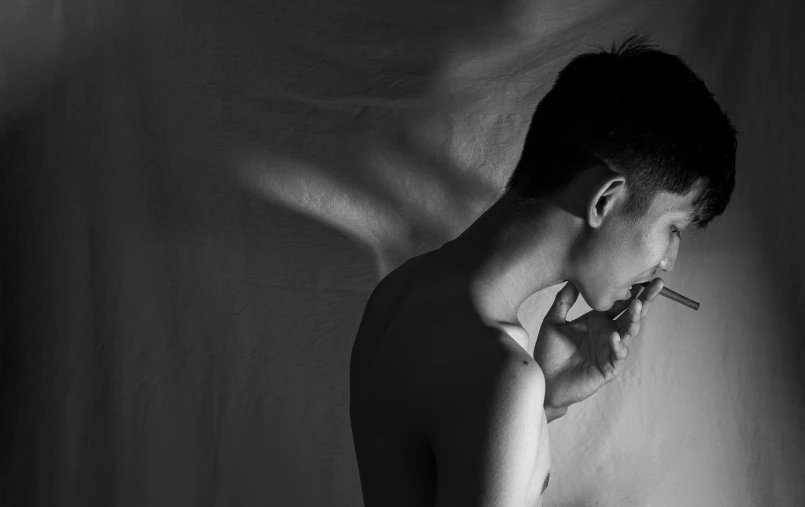 black and white pograph of shirtless male smoking a cigarette