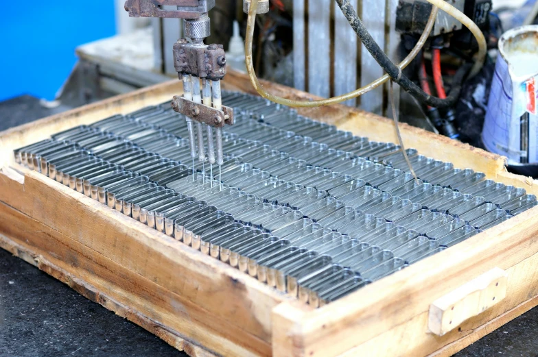 a machine that is making metal strips on some wood