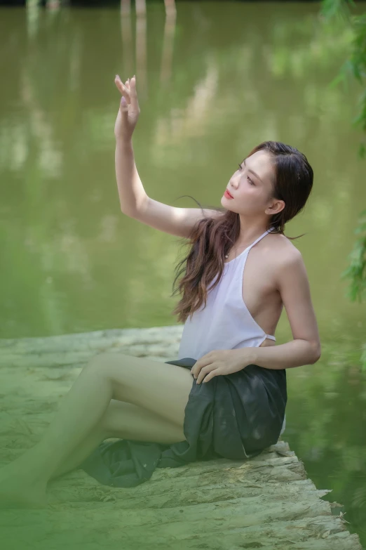 the woman sits in the water and holds her hand up