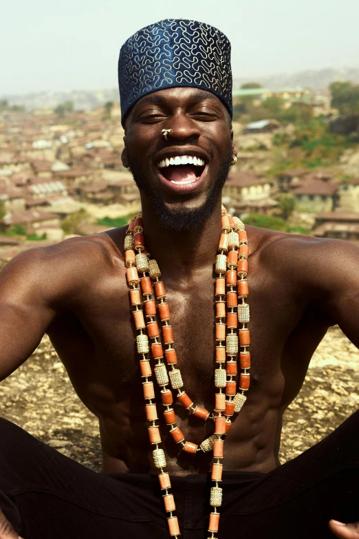 a black man wearing long beads and smiling