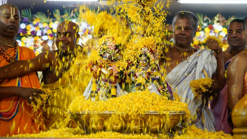 men are in front of a large pile of yellow flowers