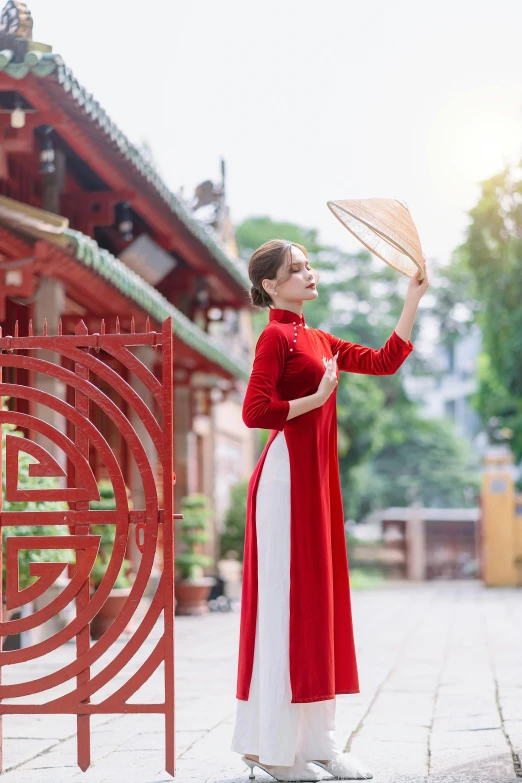 a woman standing next to an asian building holding a large white fan