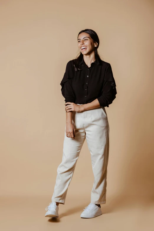 a woman wearing an all black shirt and pants is standing up and smiling