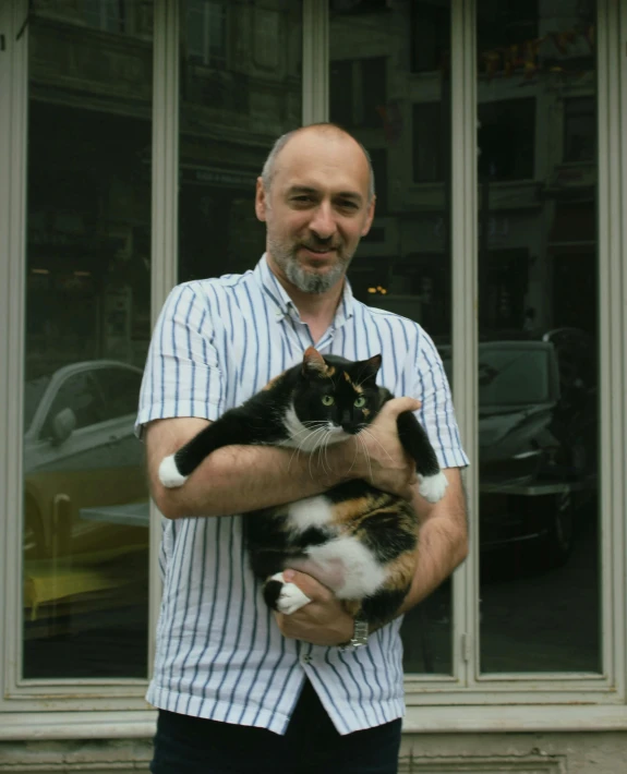 a man is holding a cat outside a building