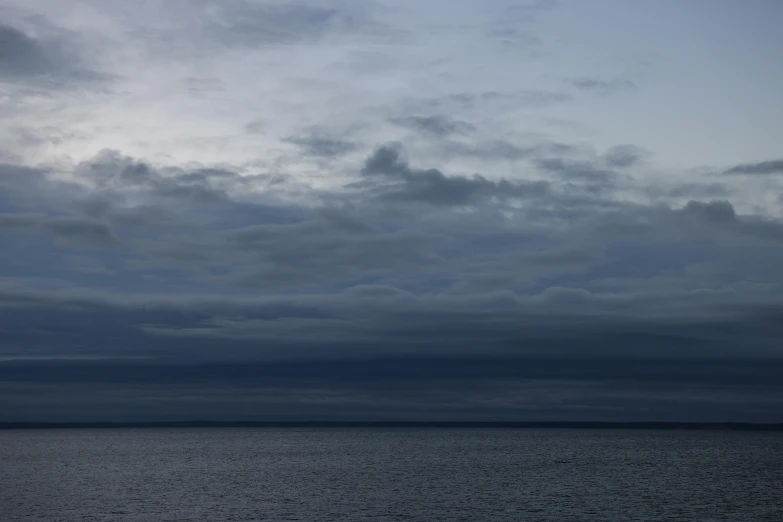 a airplane flying through cloudy skies near the ocean