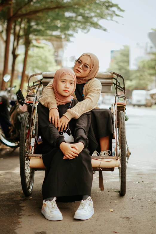 two young women sitting on top of a rickshaw in front of parked motorcycles