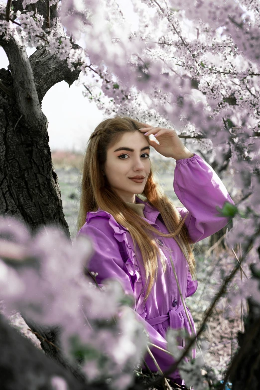 a girl in purple standing underneath a tree