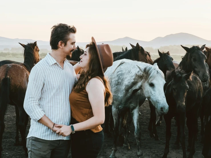 a couple emcing each other with horses in the background