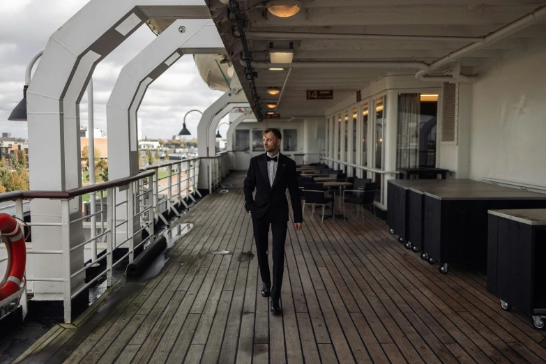 the man is wearing a black suit while walking down the ship