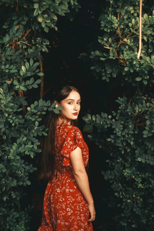 a woman stands on top of a hill in a red dress