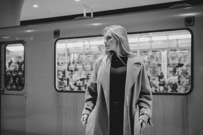 a woman standing in the subway looking at soing