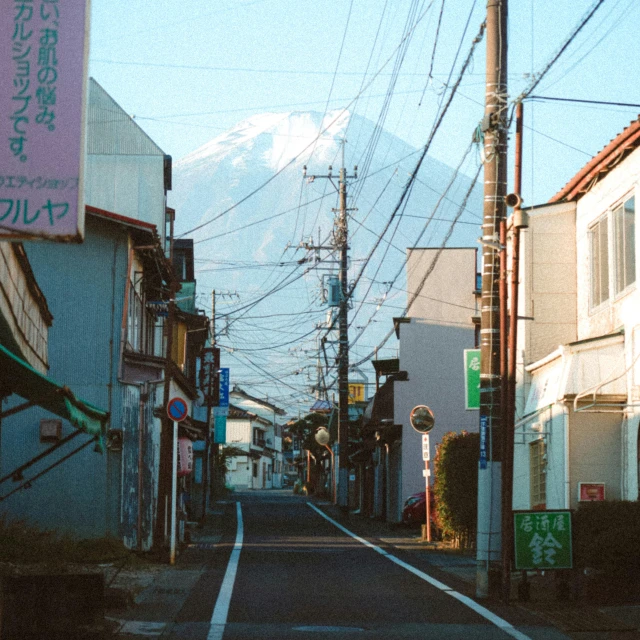 the street is lined with small stores and electric wires