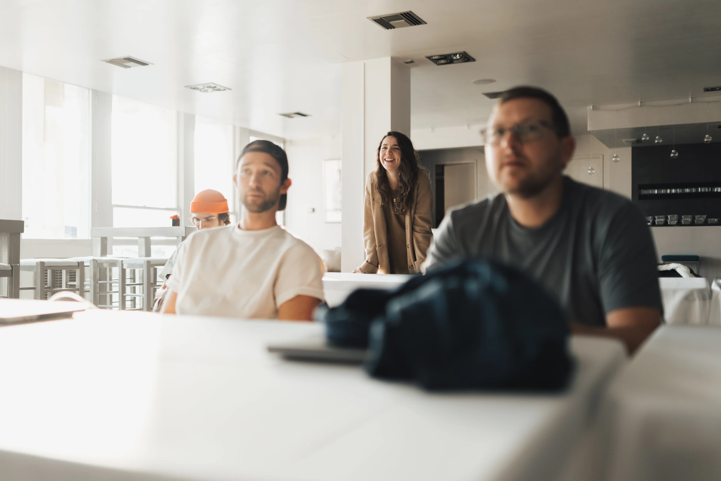 three men sit in a large white room