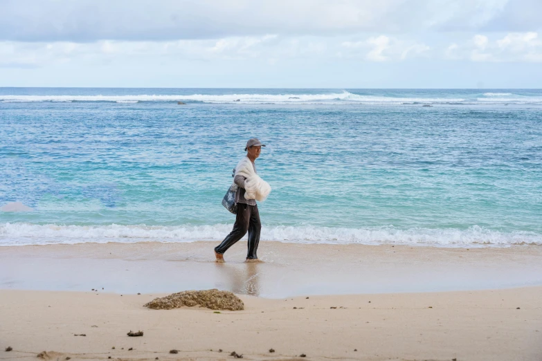 a man walking along the beach carrying his belongings