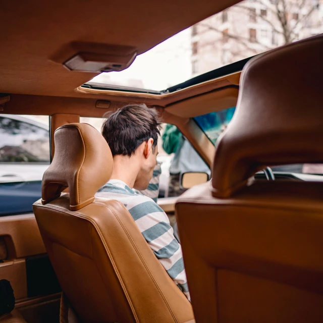 man sitting in leather car seat with arm rest down