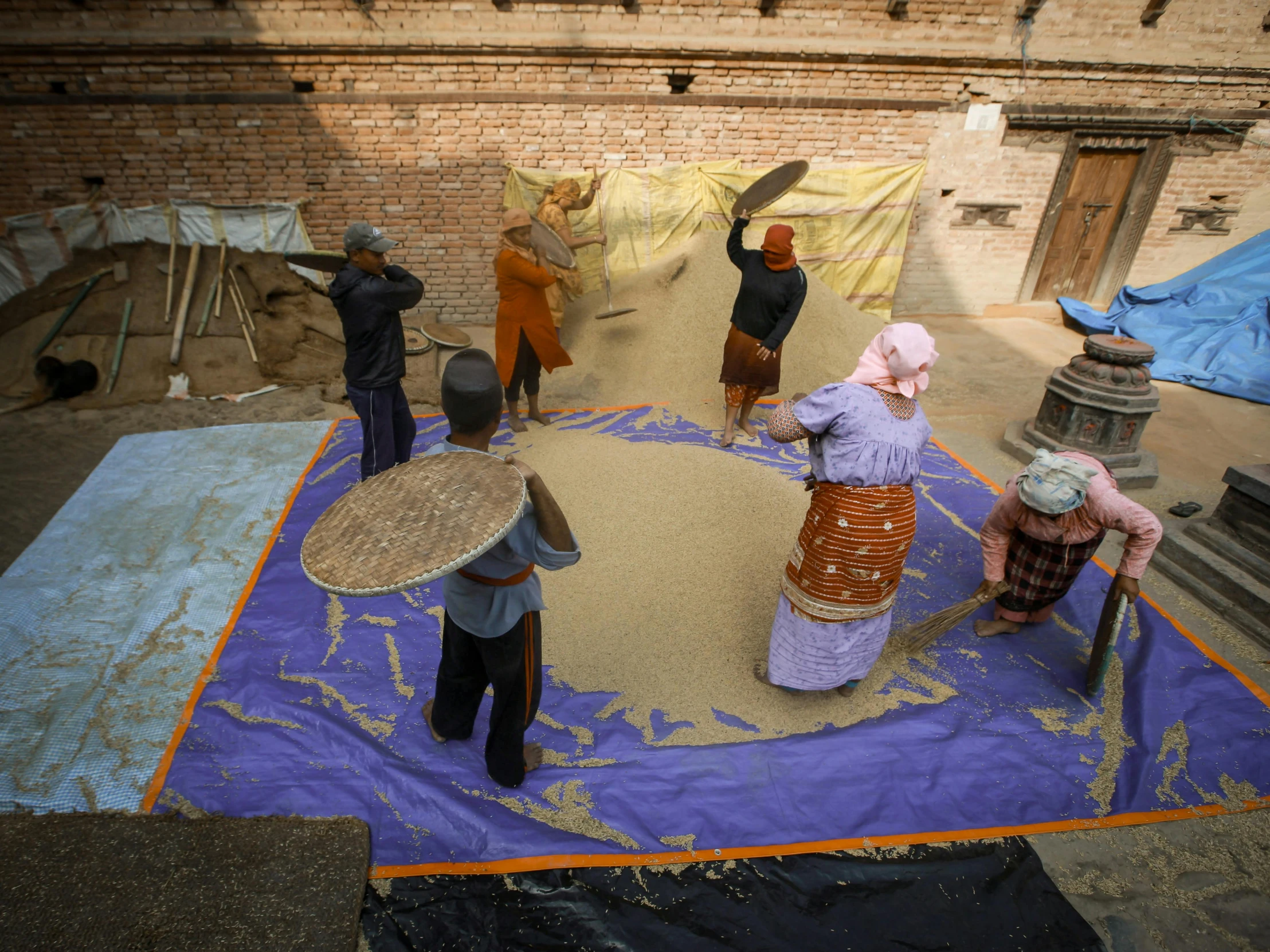 a group of women stand around sand next to a man in the center