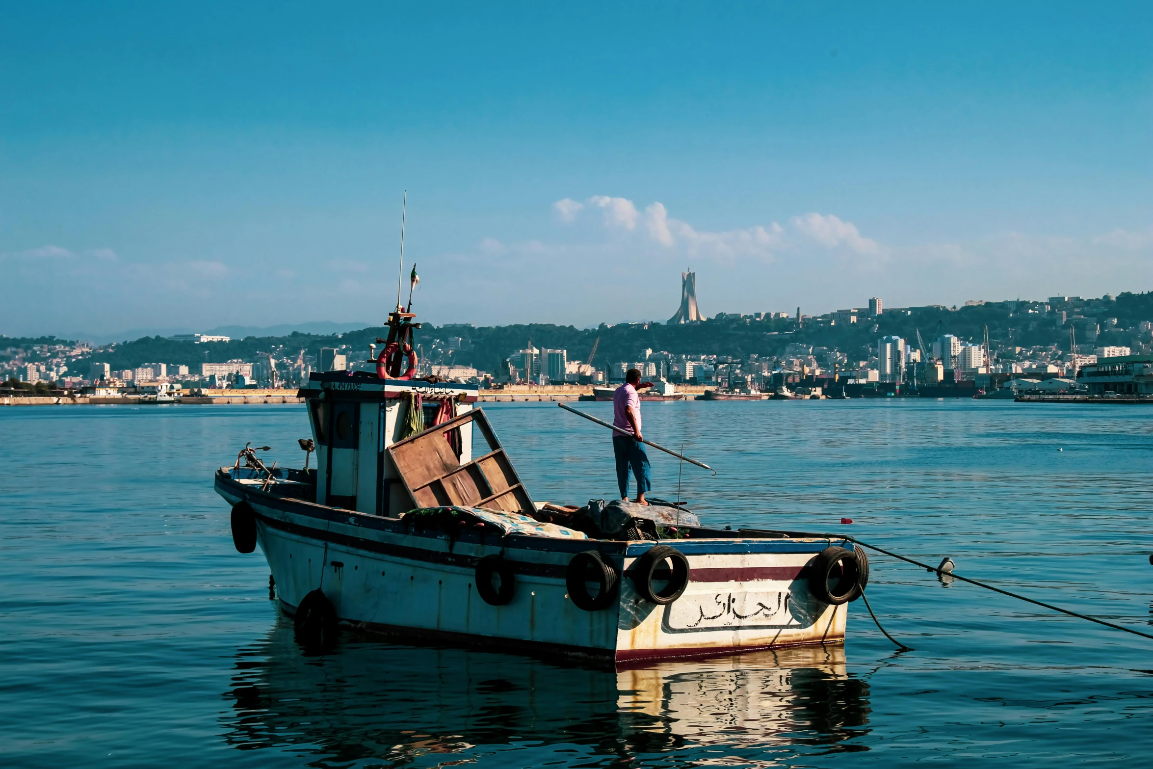 a boat on the water with a man standing on it's front end