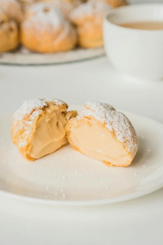 two sugary pastries are on a white plate next to a cup of coffee