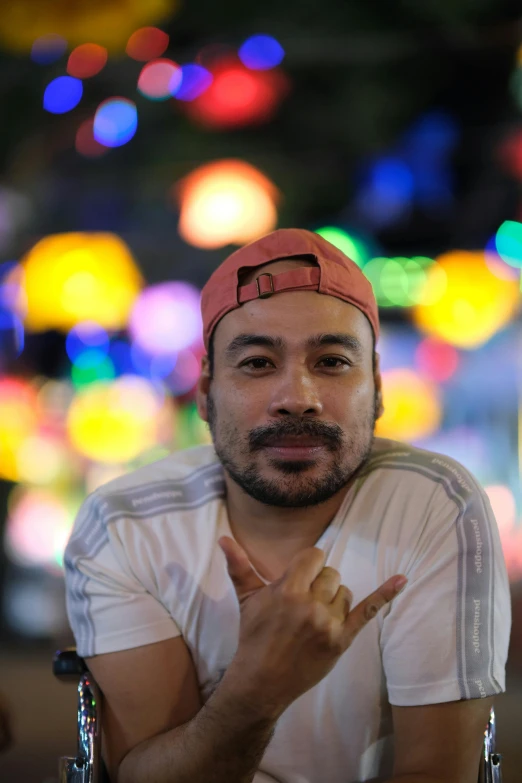 a man making a weird gesture in front of blurred lights