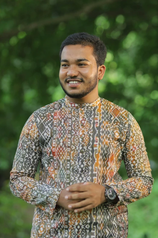 a man with a colorful shirt on standing in front of trees