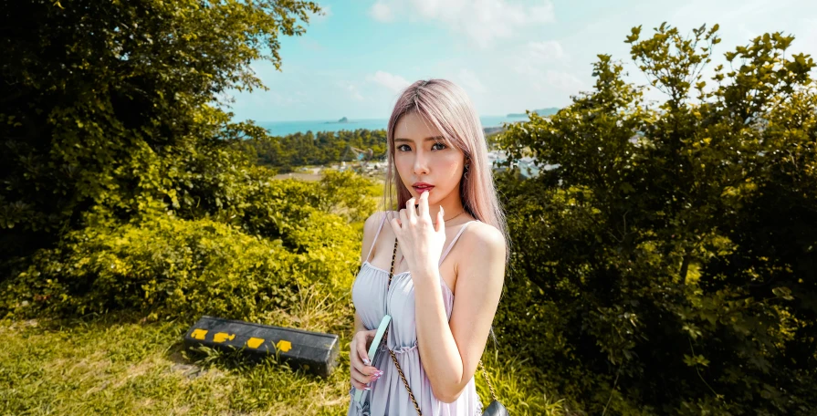 a woman posing in the grass next to a tree