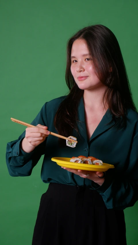 there is a woman holding two chop sticks and a bowl of sushi