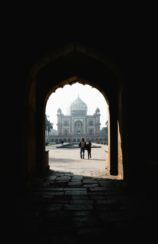 people are walking through a doorway at the end of an old building