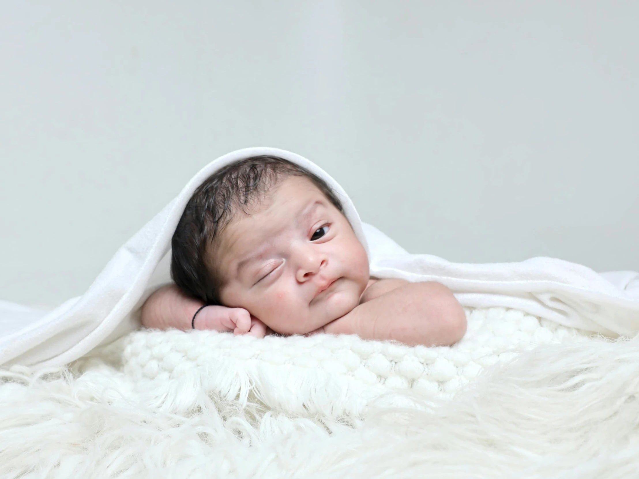 a baby is wrapped in white blanket on a white blanket