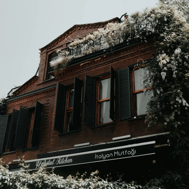 a tall brown building sitting next to flowers and trees