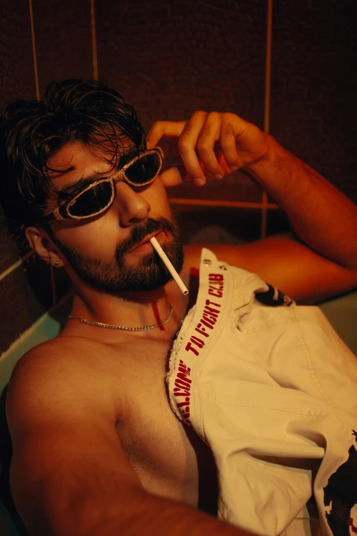 a man is in sunglasses smoking soing while sitting in a bathtub