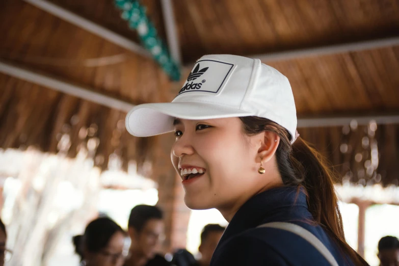 a young woman with a hat smiles as she stands outside