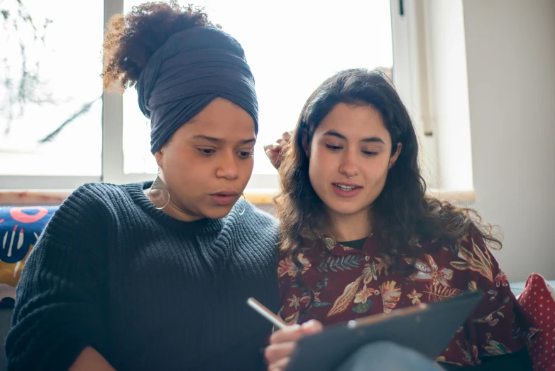 two girls sitting down looking at soing on a tablet