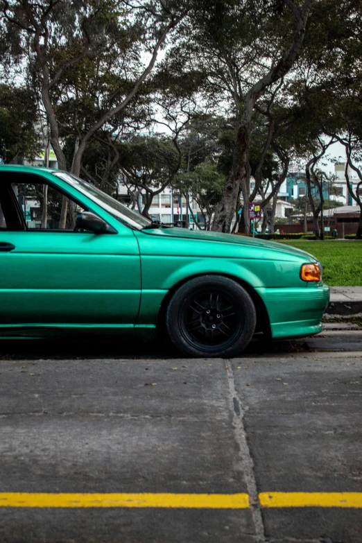 a teal car is parked near a street curb