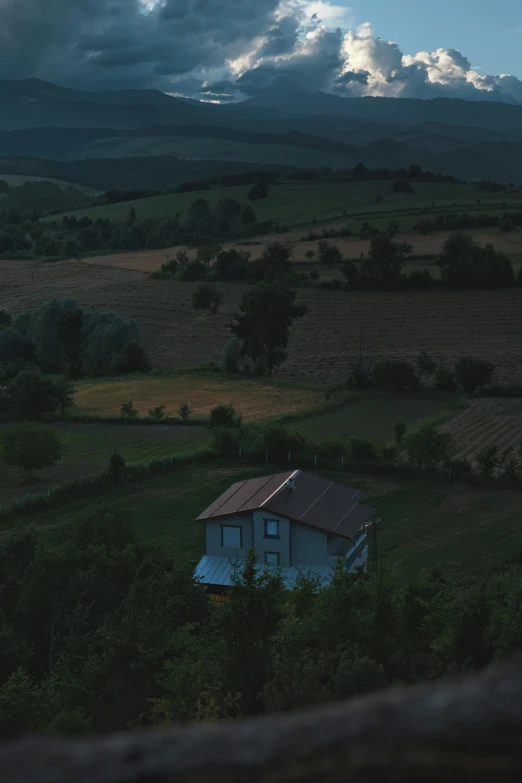 a barn nestled between some hills is pictured at sunset