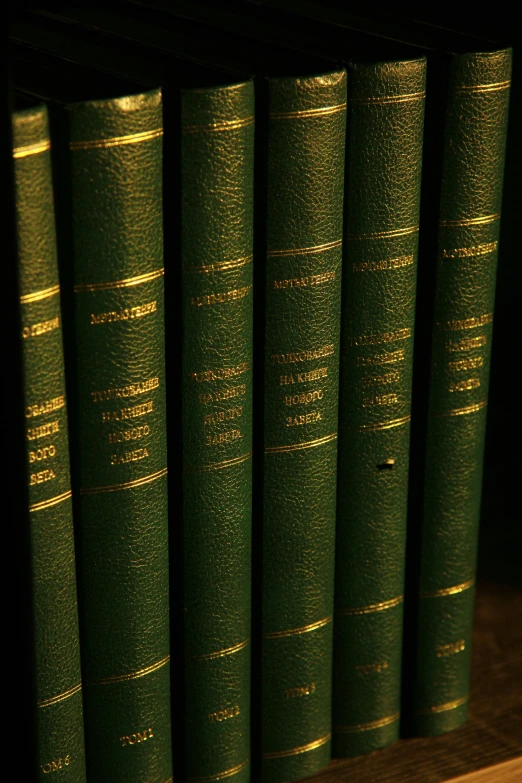 five books in green bindings sit on a shelf