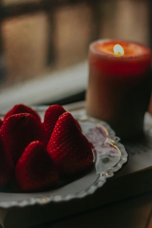 strawberries on a plate on a table with a lit candle