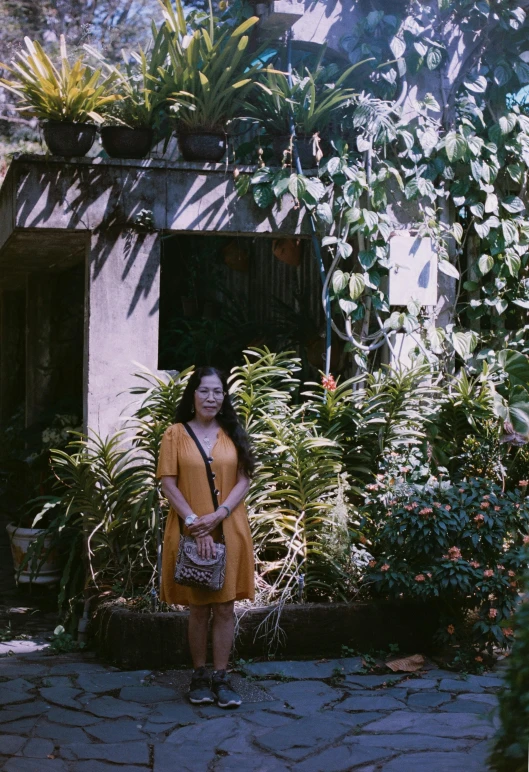 woman in a yellow dress standing outside near trees