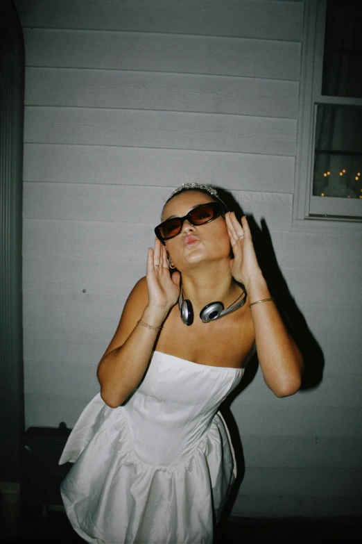 a woman posing with her hands up wearing sunglasses