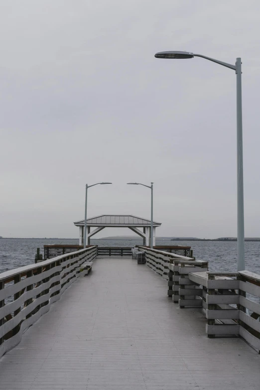 empty bench along a pier on a cloudy day