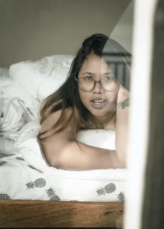 a girl lies on her bed and stares out the window