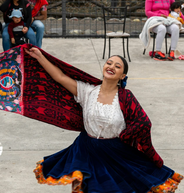 a woman is wearing an ethnic skirt and posing with her shaw around her shoulders