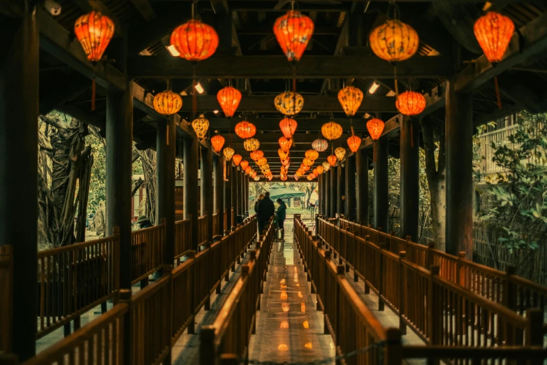 a view down a long wooden walkway covered in lanterns