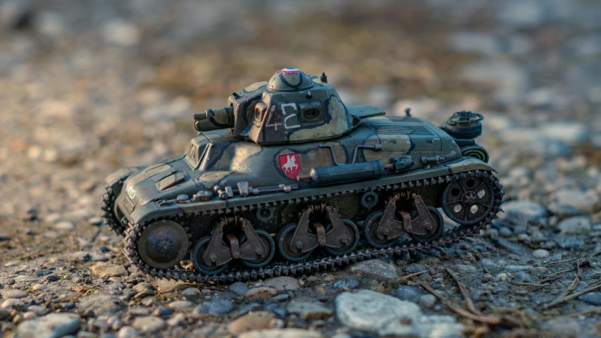 a toy tank is on the ground with rocks around